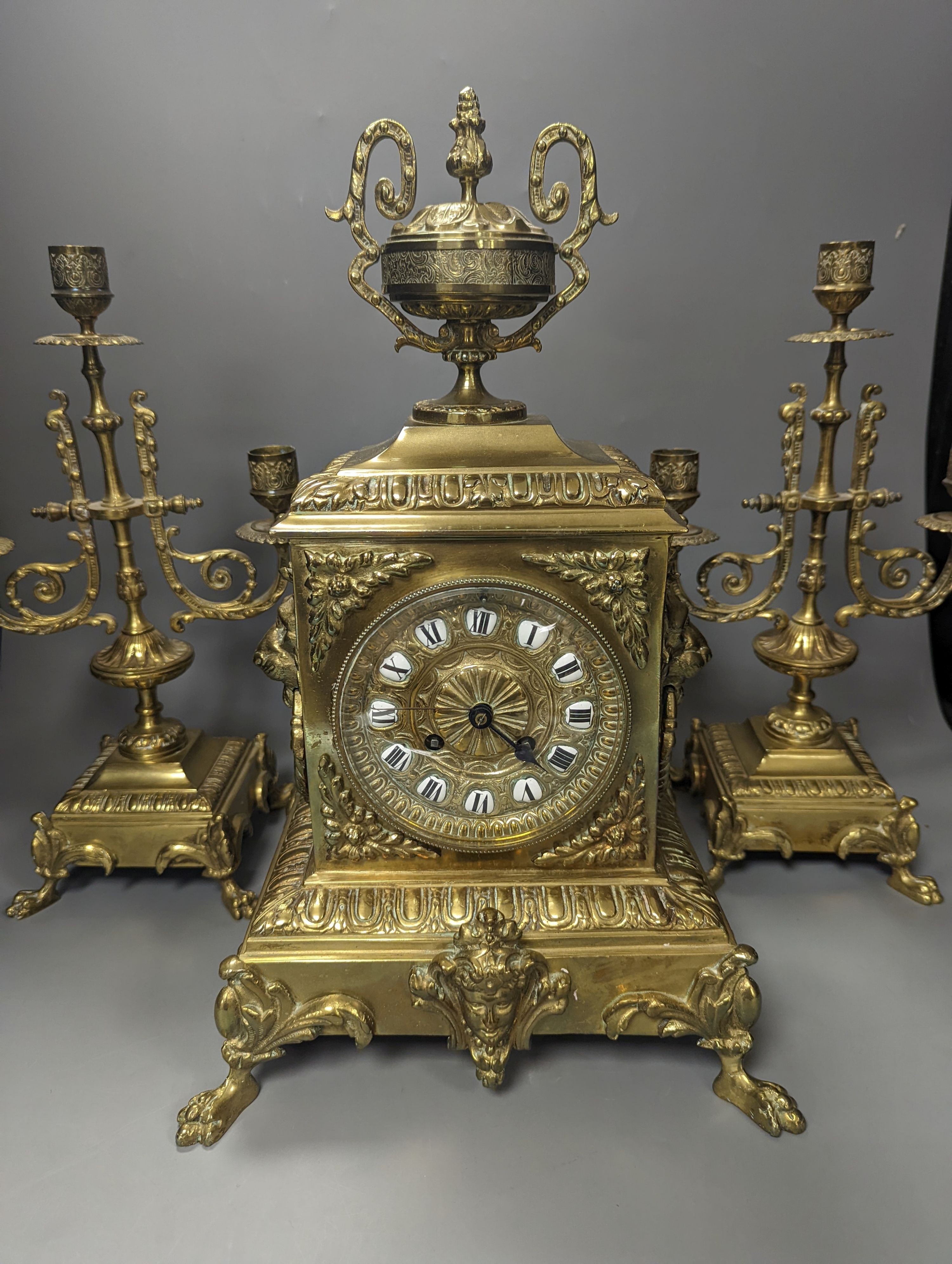 A 19th century French ornate brass clock garniture including a pair of 3 branch candelabra, Clock 42 cms high.